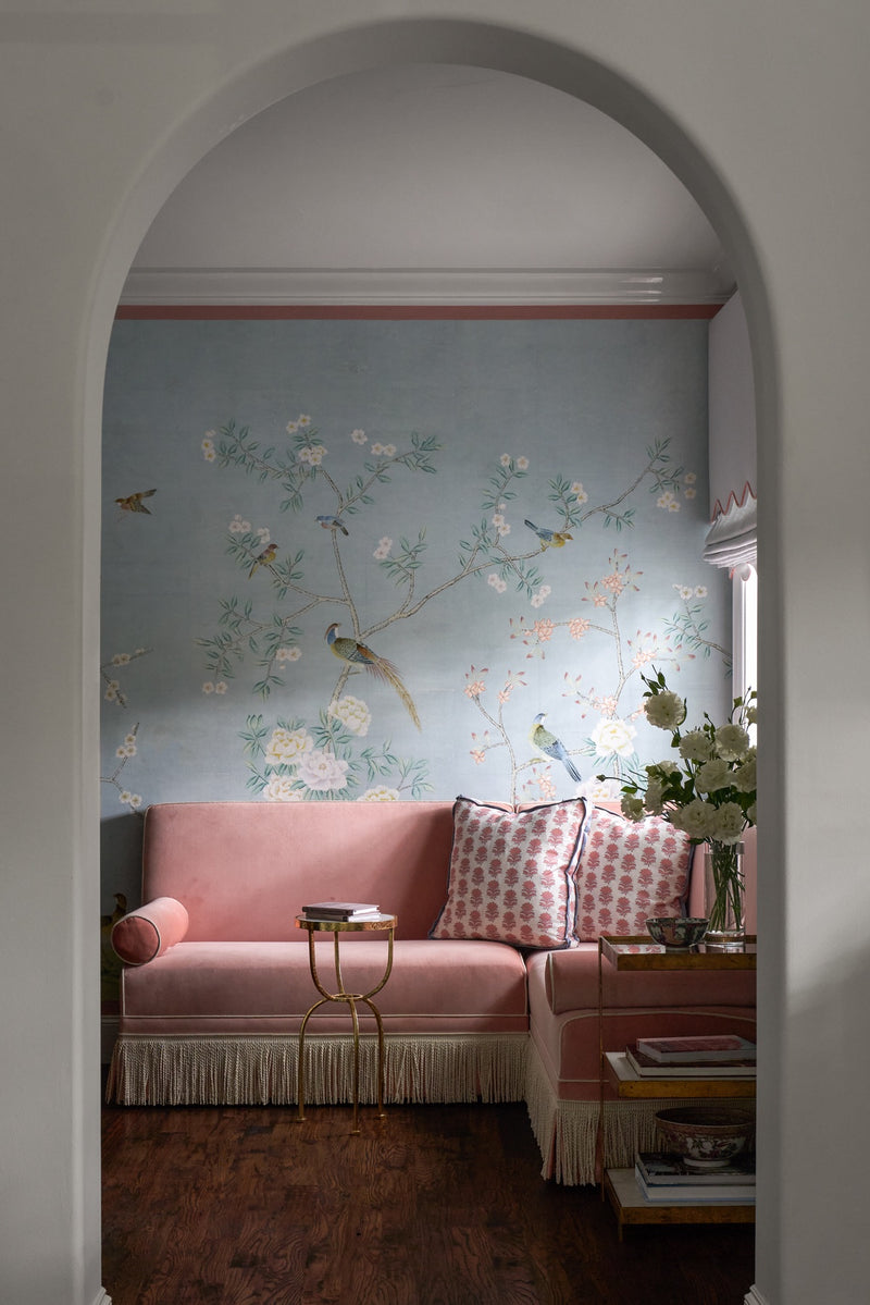 Decorative painted wallcovering with birds behind a pink sofa