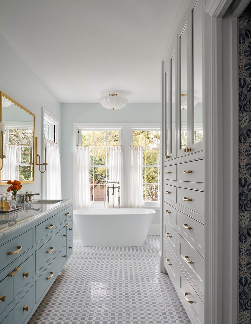 View of bathroom area with tub and blue cabinets