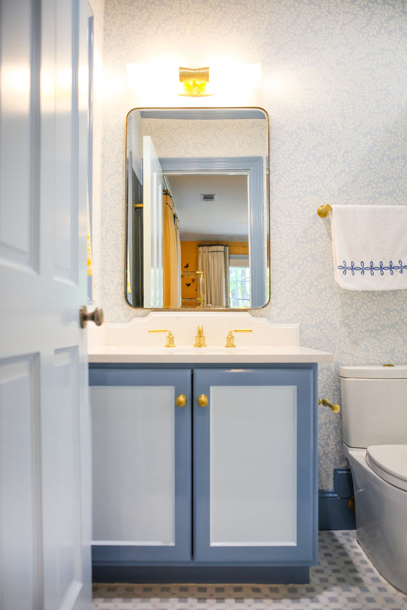 Bathroom with a two-tone blue vanity and brass accents
