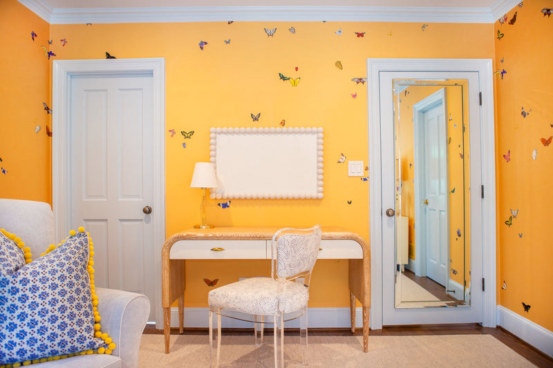 Second view of yellow bedroom with butterfly wallpaper, view of a desk and mirror 