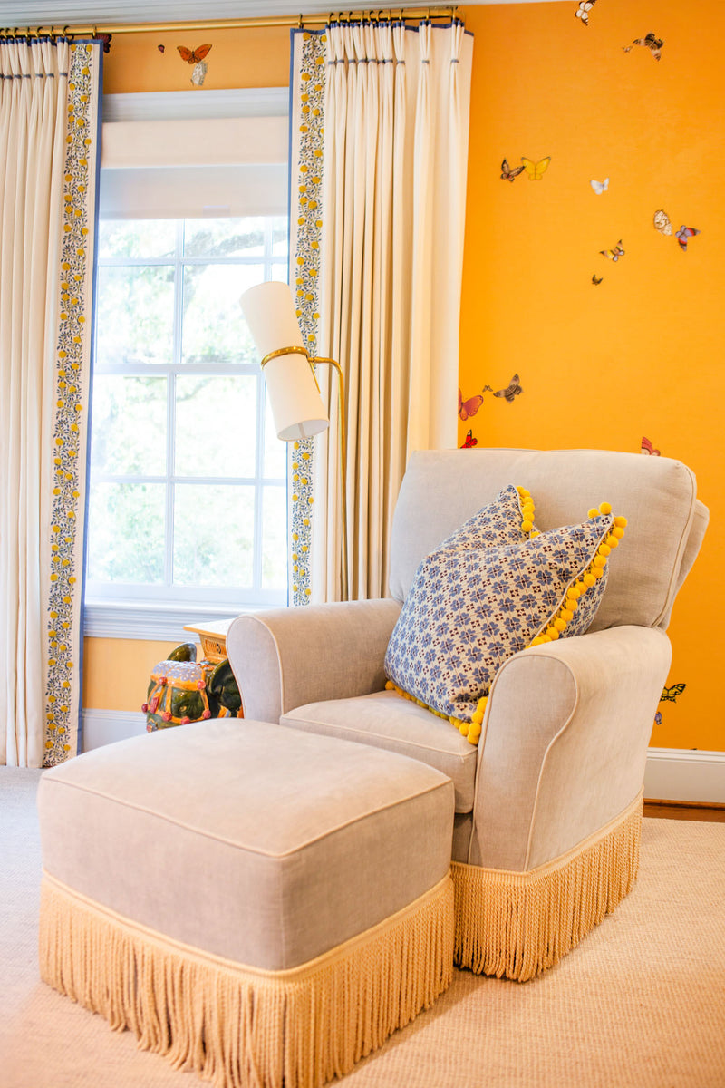 Third view of yellow bedroom with butterfly wallpaper with a blue chair with coordinating ottoman 