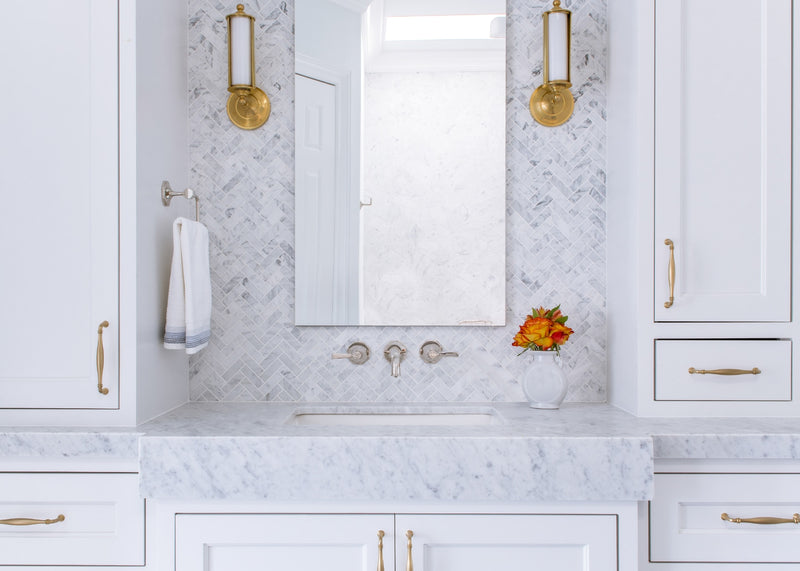 White marble sink surrounded by white cabinetry