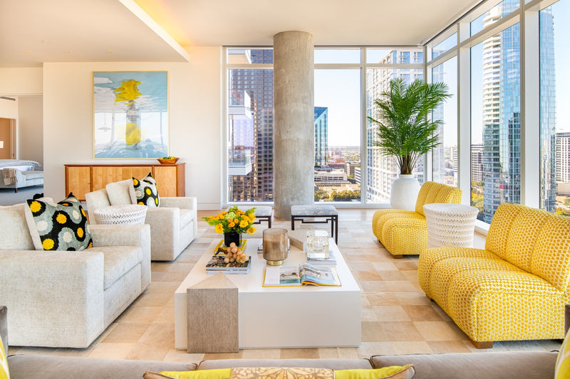 Living room area with coffee table, lounge chairs, and yellow sofa